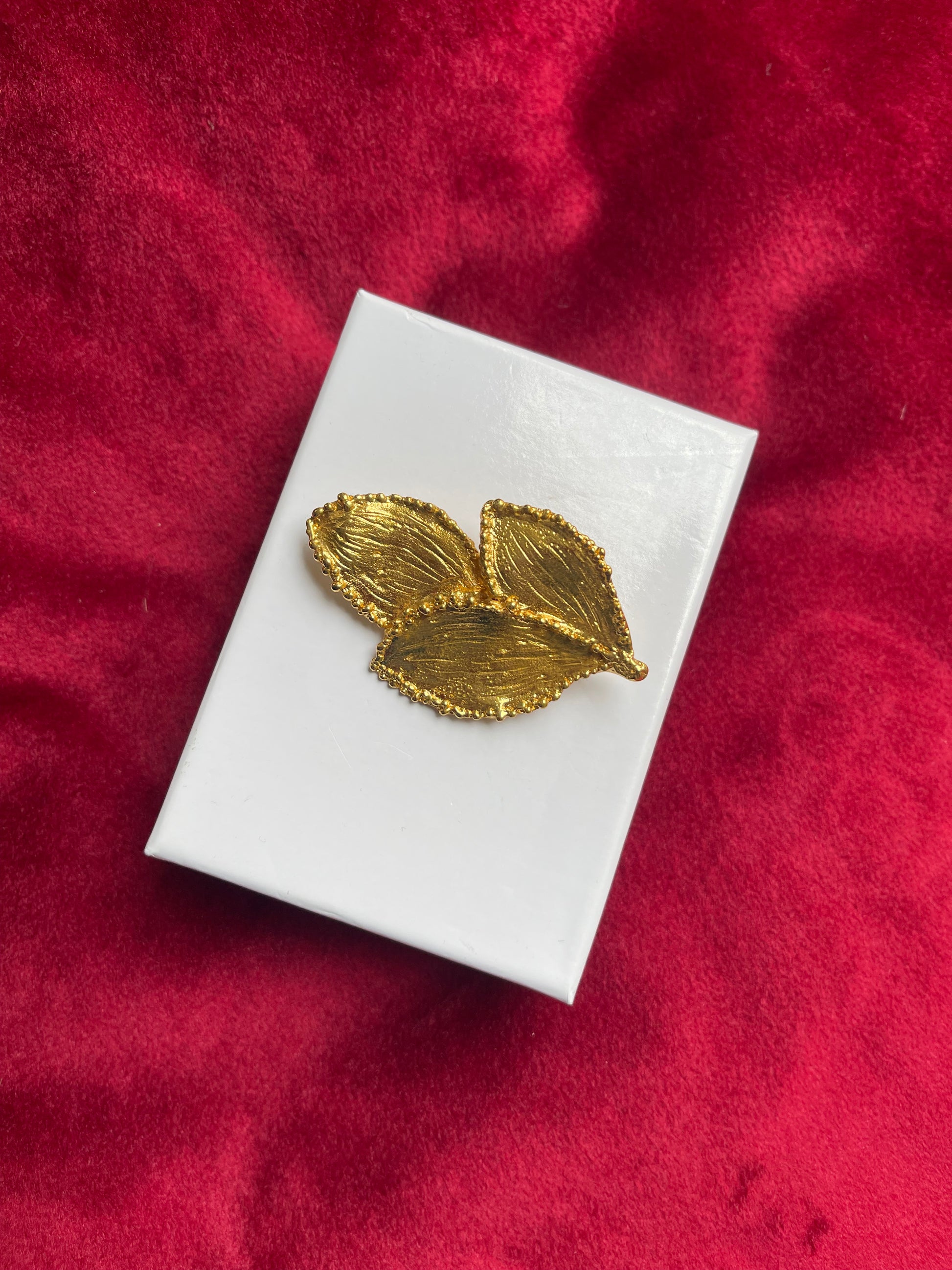 Rare Vintage Yves Saint Laurent 80s 90s gold tone leaf brooch excellent condition on white and red background 