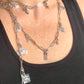 Close up on two upcycled Dior Beauté phone charm necklace with removable silver-tone charms worn by model styled differently 