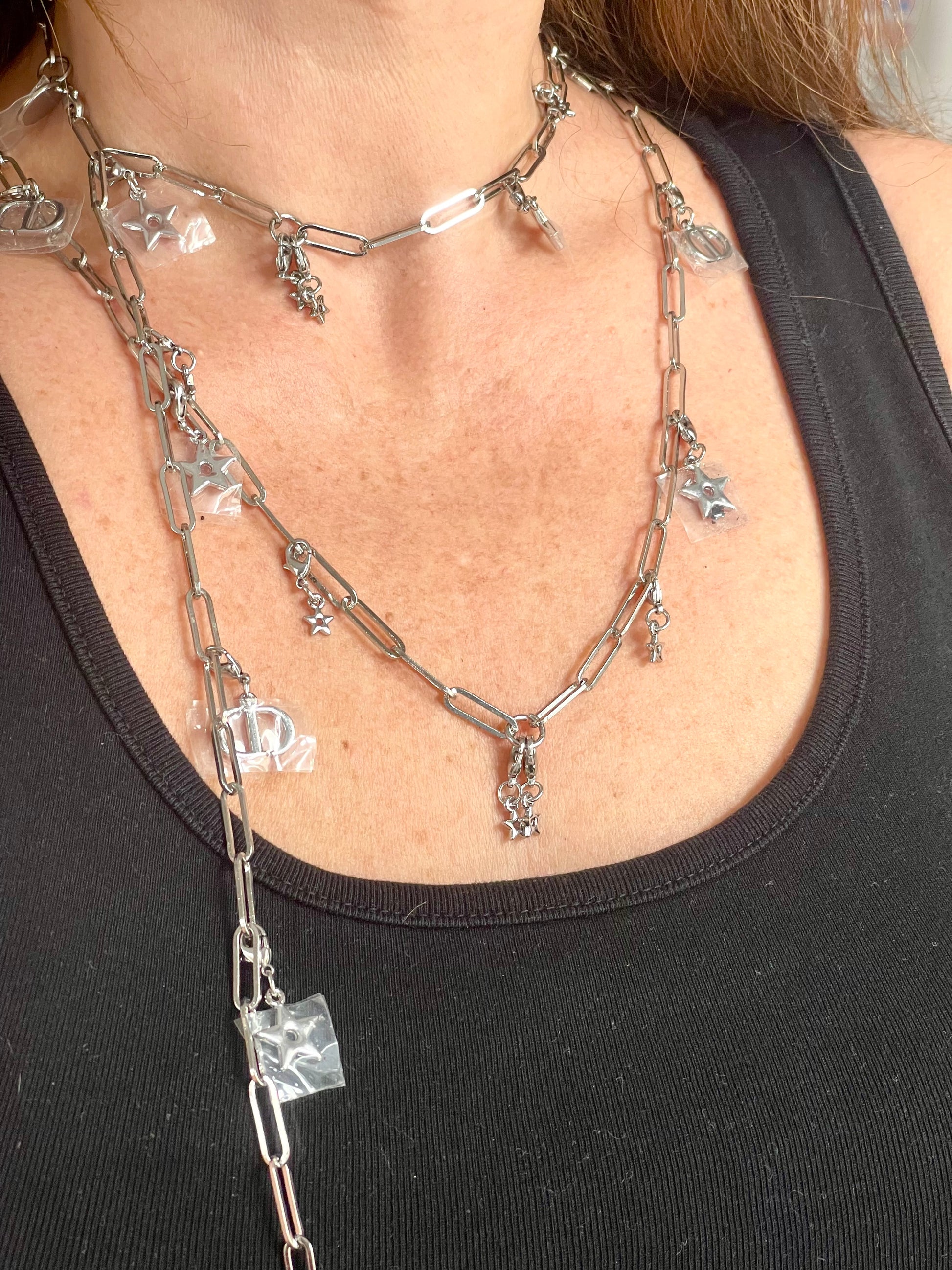 Close up on two upcycled Dior Beauté phone charm necklace with removable silver-tone charms worn by model styled differently 