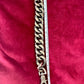 Using a measuring tape Top view Preloved YSL bronze and grey chain worn as a statement piece against red velvet background 