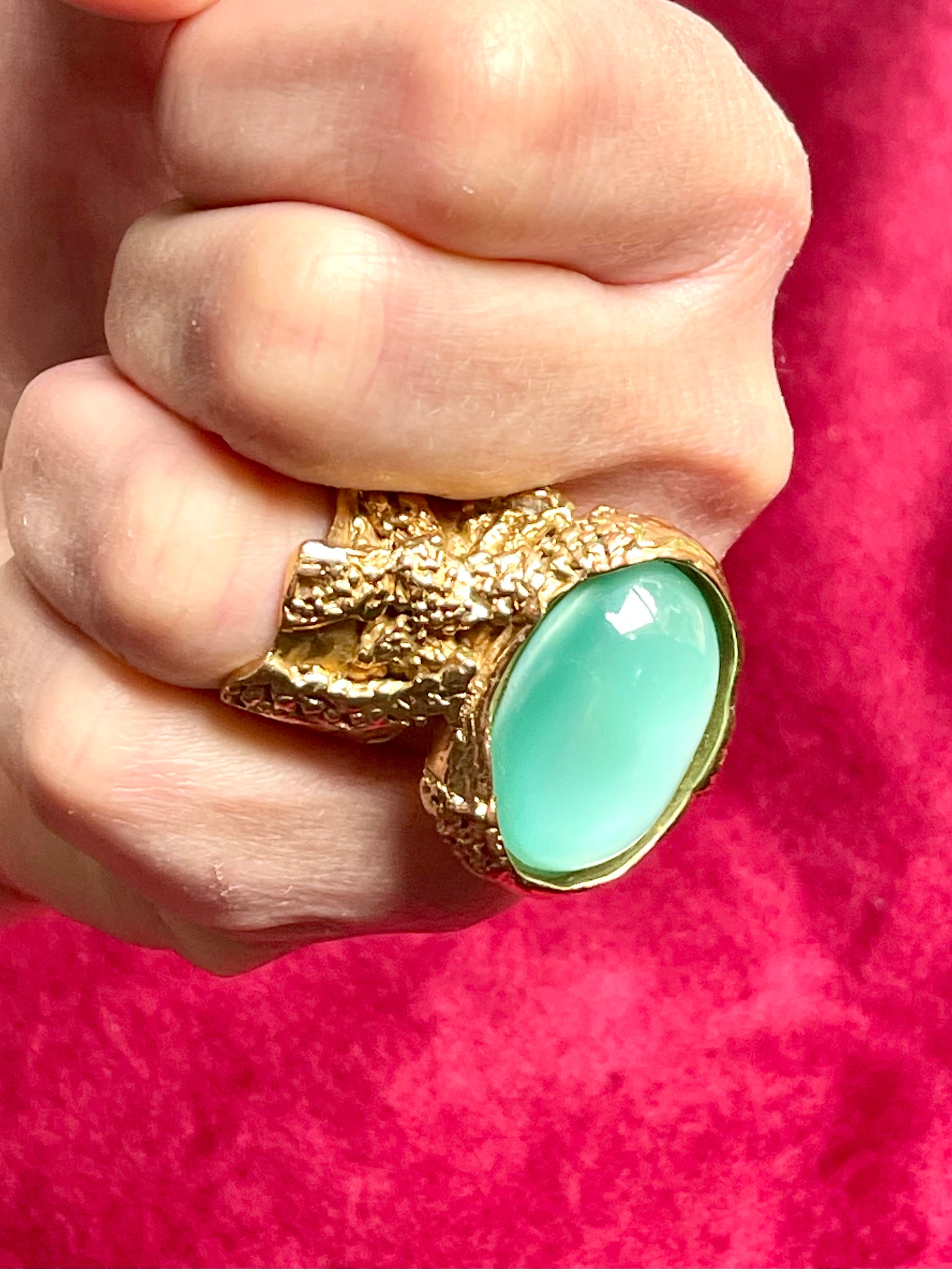 Close-up of the luminous turquoise nacre stone in a vintage gold Yves Saint Laurent arty ring, highlighting its glossy finish and organic setting , worn by model 