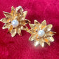 Closeup on Vintage Yves Saint Laurent gold-tone floral earrings with pearl center, signed YSL Made in France, 1980s designer jewelry.