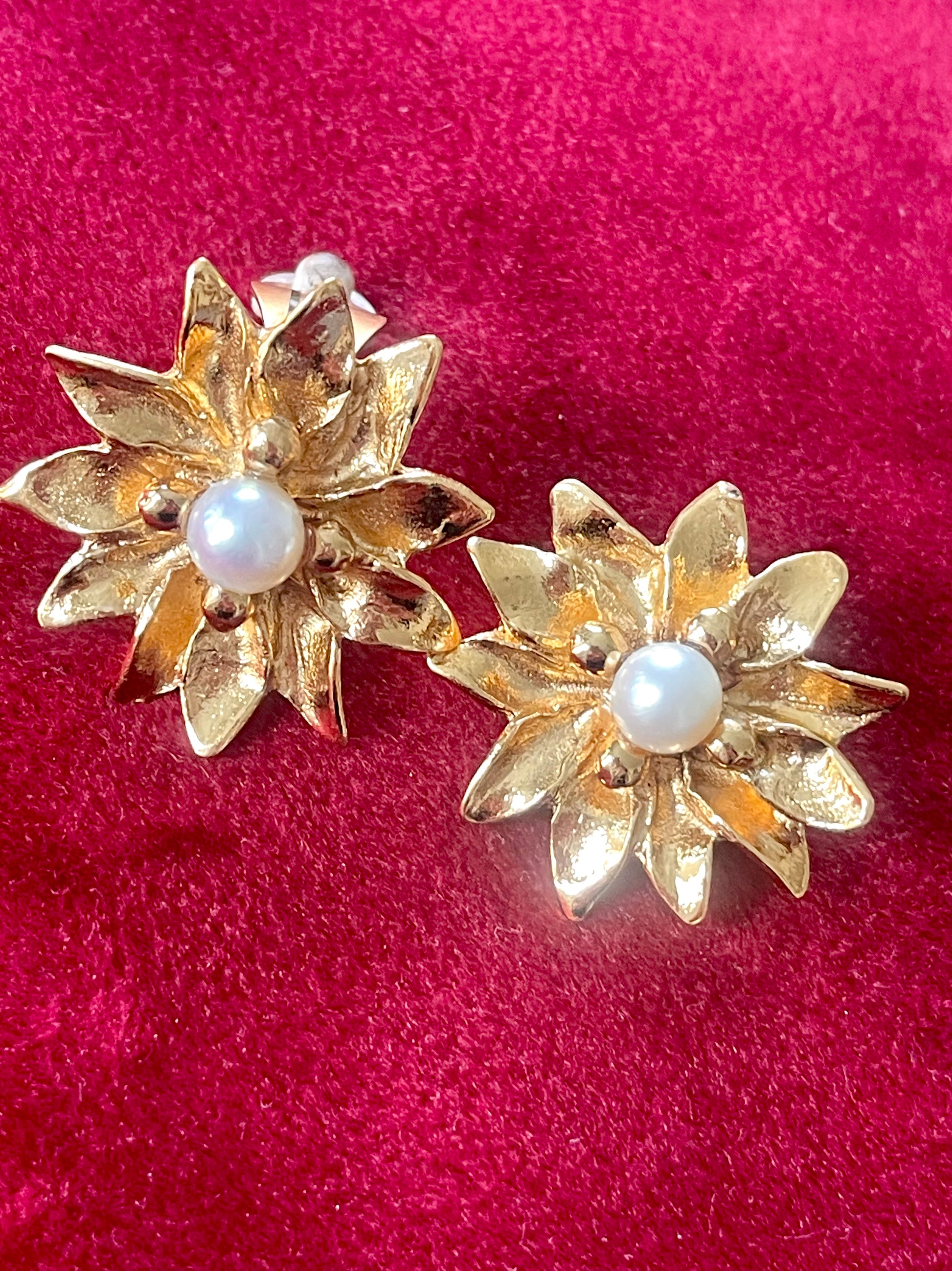 Closeup on Vintage Yves Saint Laurent gold-tone floral earrings with pearl center, signed YSL Made in France, 1980s designer jewelry.
