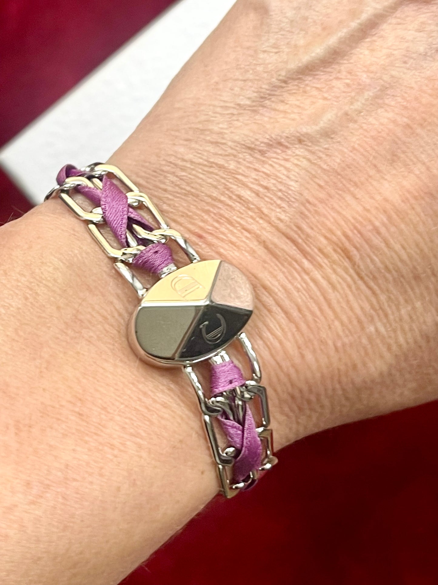 Authentic vintage Christian Dior bracelet clasp signature On a wrist against a red background 