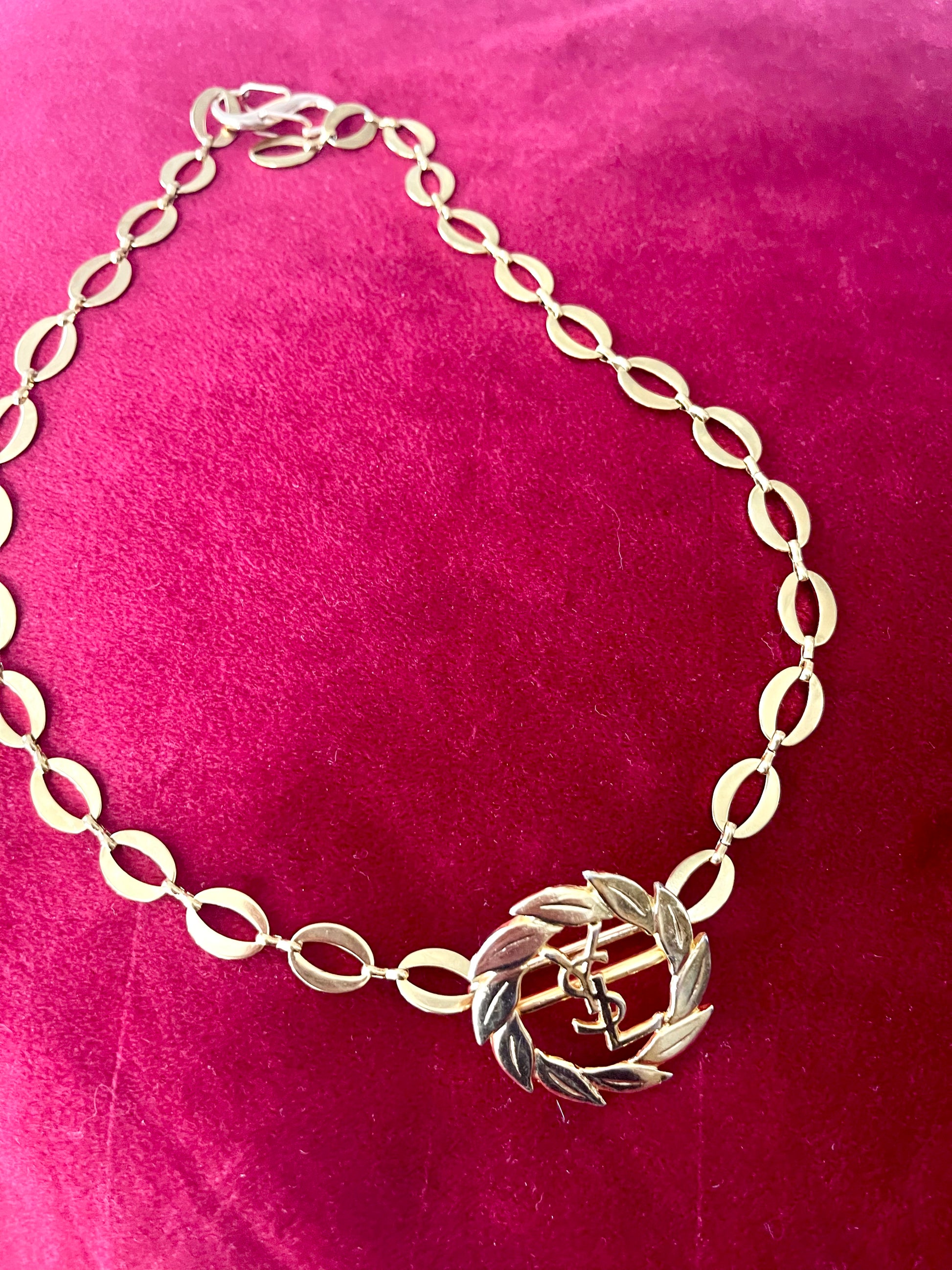 Top view of a refurbished vintage YSL laurel wreath pendant mounted on a gold-plated stainless steel necklace, with adjustable hoop links and a slightly lighter-toned closure.