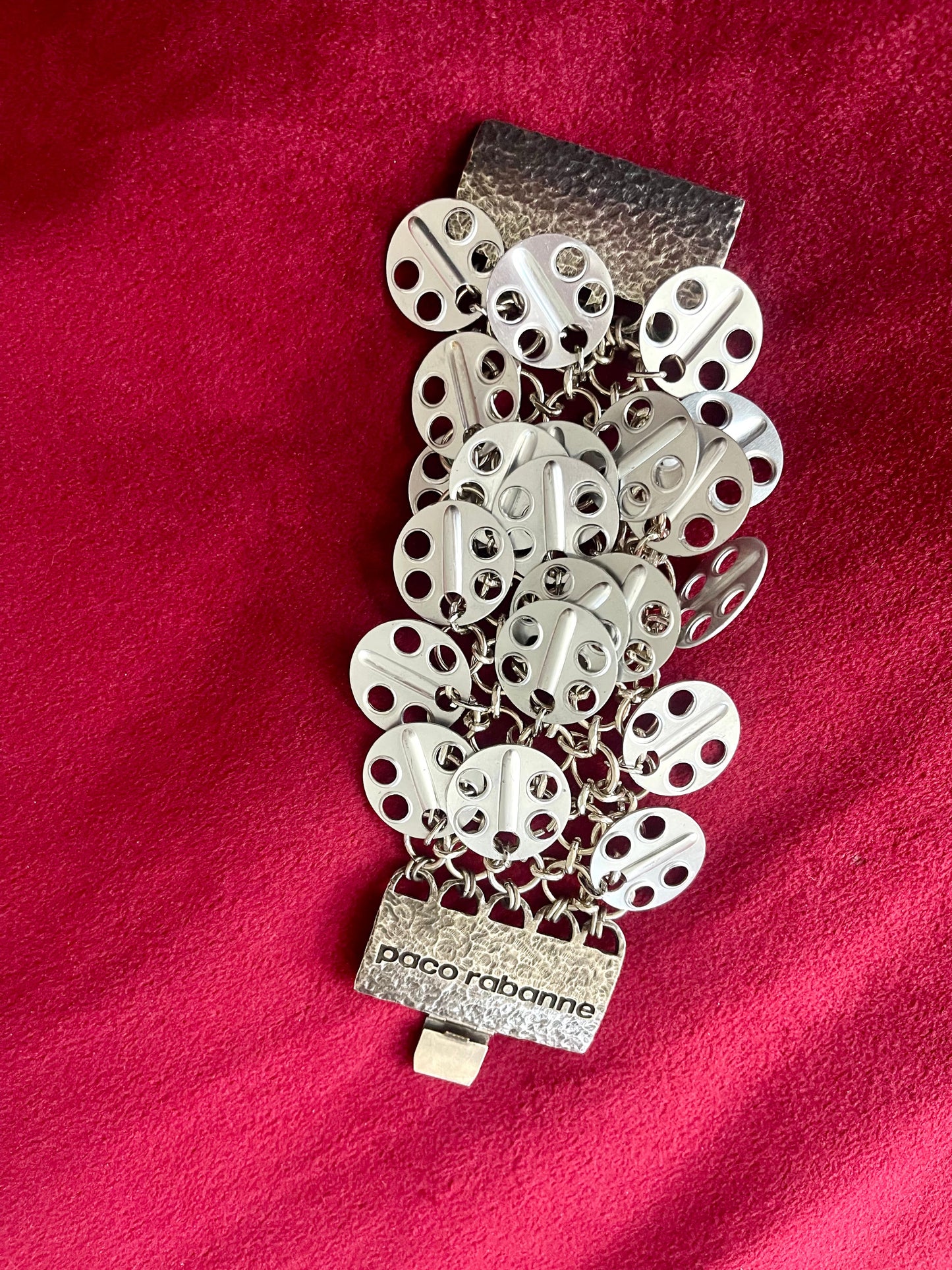 Signed Paco Rabanne vintage disc bracelet close-up Top view on red background 