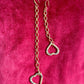 Yves Saint Laurent upcycled heart pendant earrings, front view on pink background