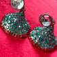 Close-up of Yves Saint Laurent Rive Gauche vintage statement earrings with turquoise and red rhinestones showing the imperfections with a red velvet background 