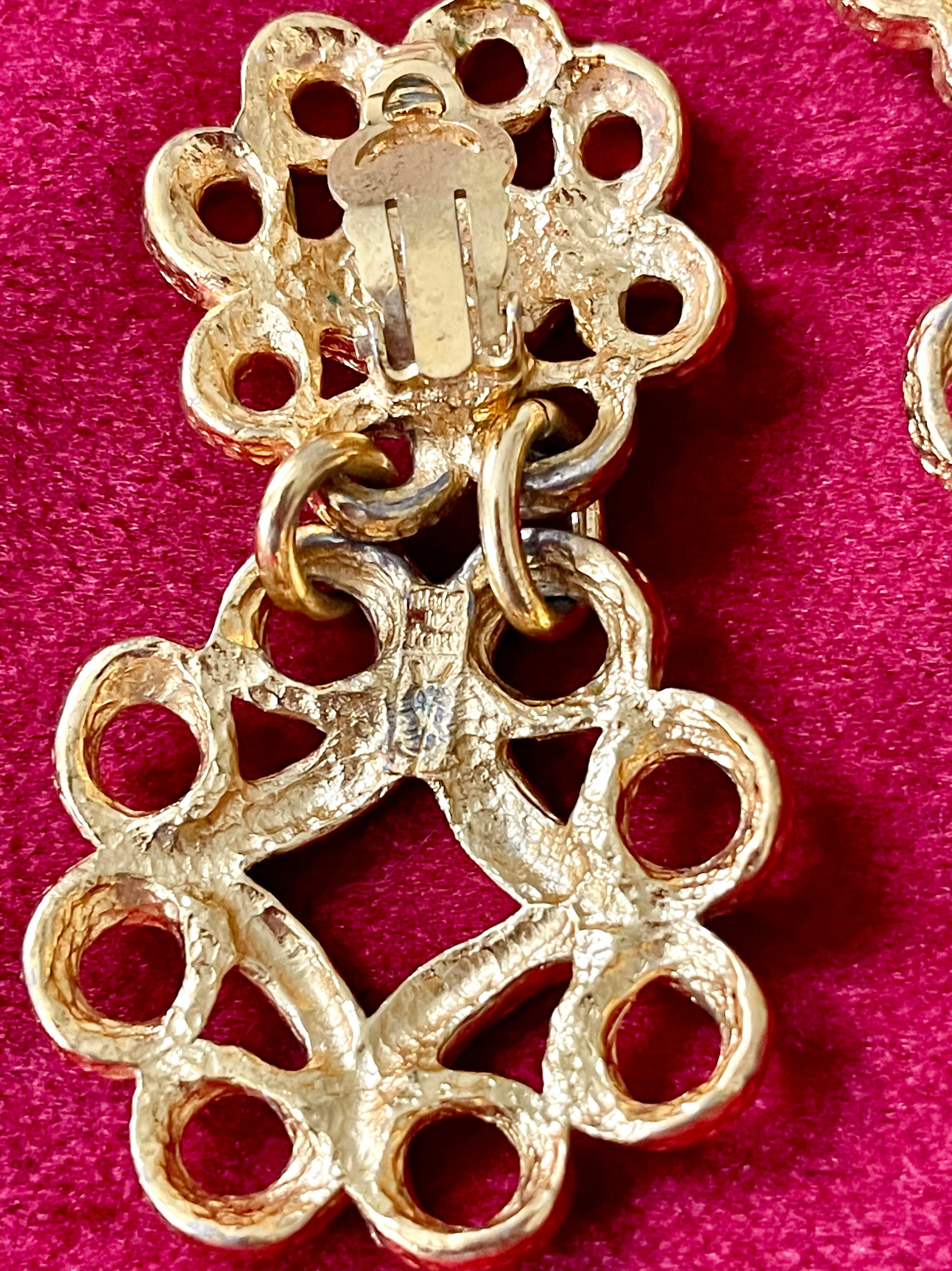 Close up on Back view of vintage YSL gold-tone earrings showing textured metal, clip-on closure, and the YSL signature mark on the lower segment