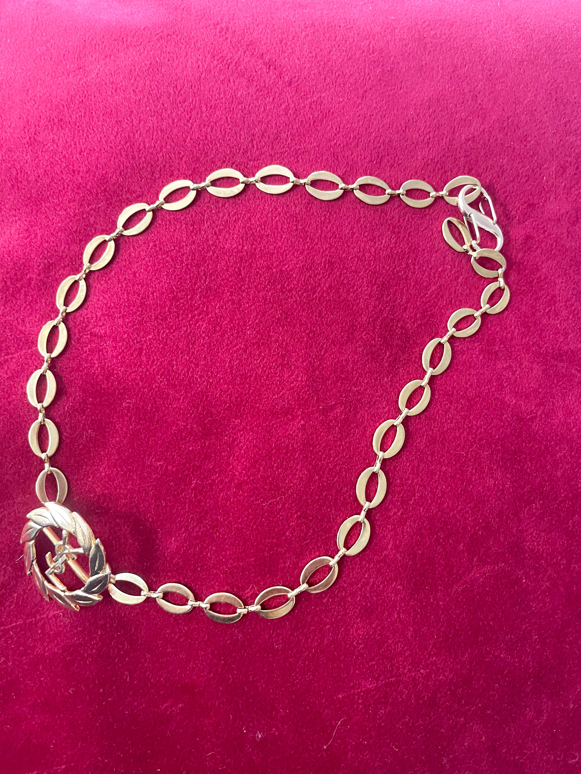 Side view of a refurbished vintage YSL laurel wreath pendant mounted on a gold-plated stainless steel necklace, with adjustable hoop links and a slightly lighter-toned closure.