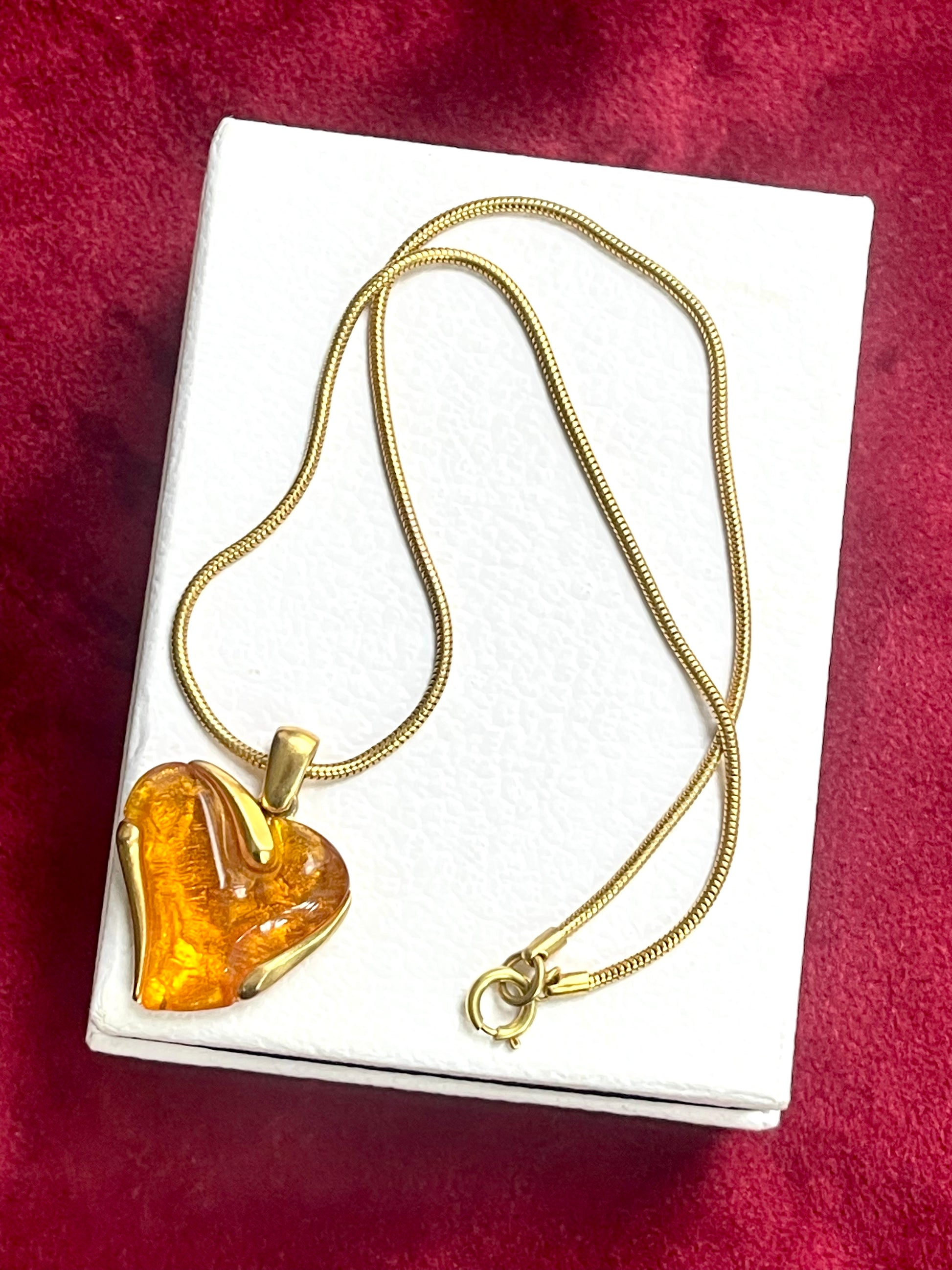 Statement vintage YSL necklace with orange resin pendant on white background
