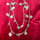 Two upcycled Dior Beauté phone charm necklace with removable silver-tone charms on a red background 