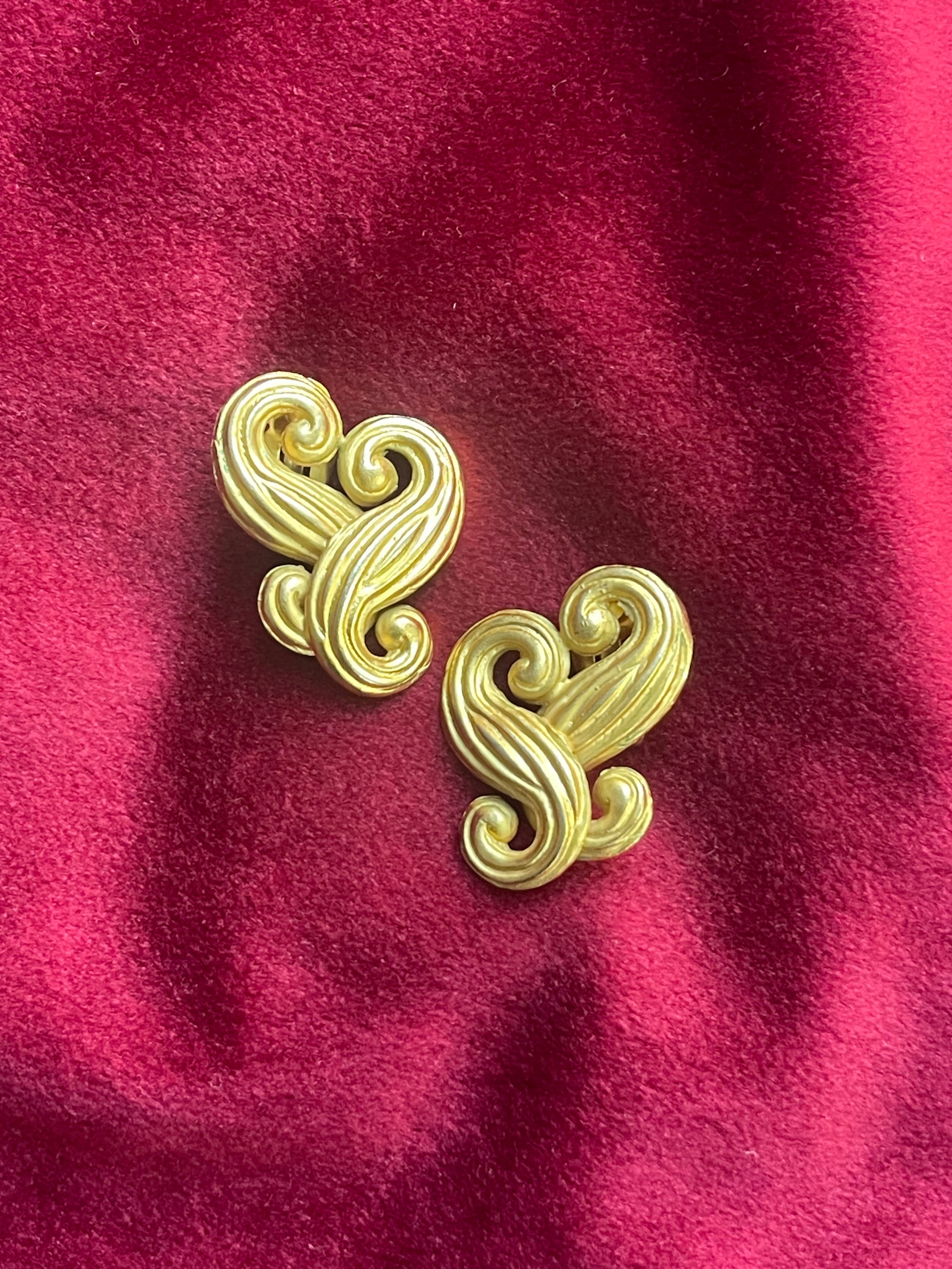 Close-up of vintage Nina Ricci swirly heart earrings in matte gold tone