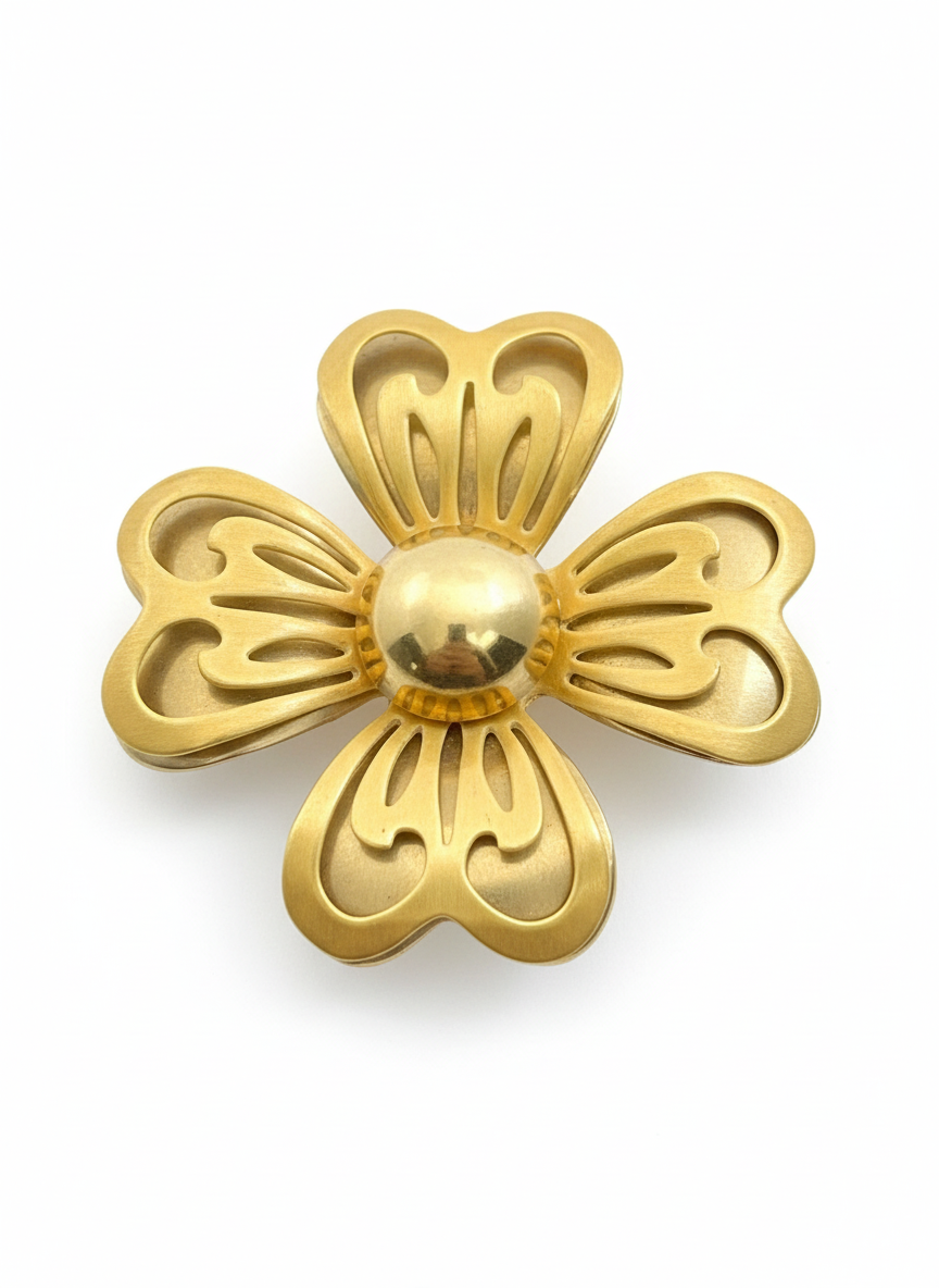 A vintage gold metal brooch with a truffle design, enamel detailing, and a central golden orb.