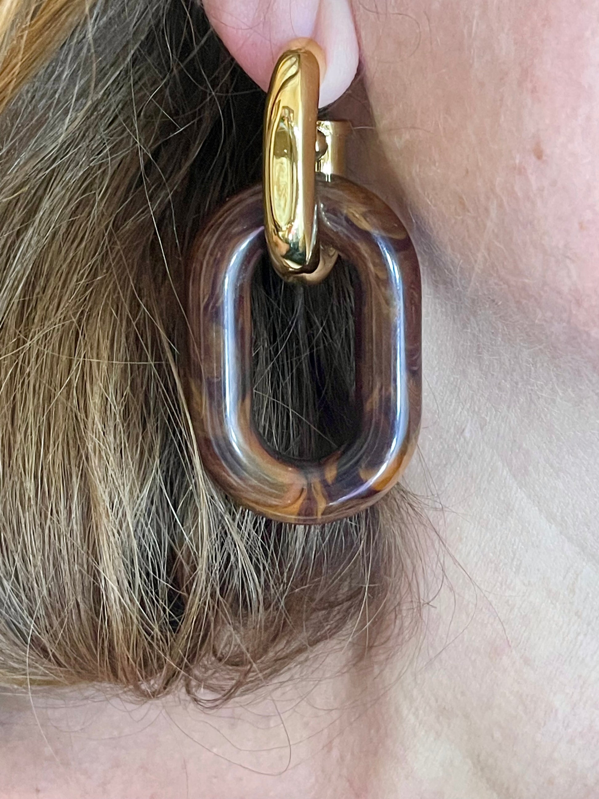 Close up Model wearing Paco Rabanne XL Link statement earrings in brown resin and gold metal, 2025 collection, luxury designer jewelry
