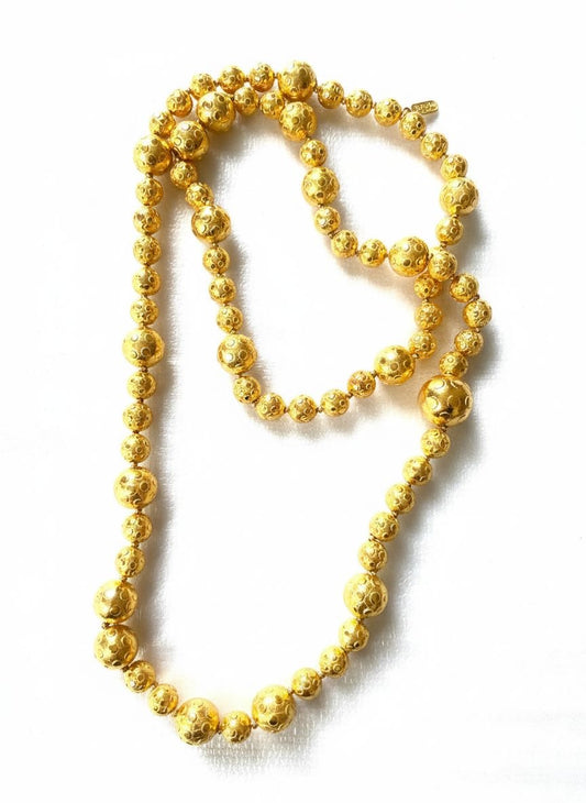 Vintage Yves Saint Laurent gold beaded necklace with textured graduated beads displayed on white background.