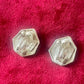 Back view of Pair of silver hexagonal Yves Saint Laurent vintage earrings on a red textured background