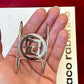Close up of Refurbished vintage Paco Rabanne Parfums cuff bracelet modernist design placed on palm 