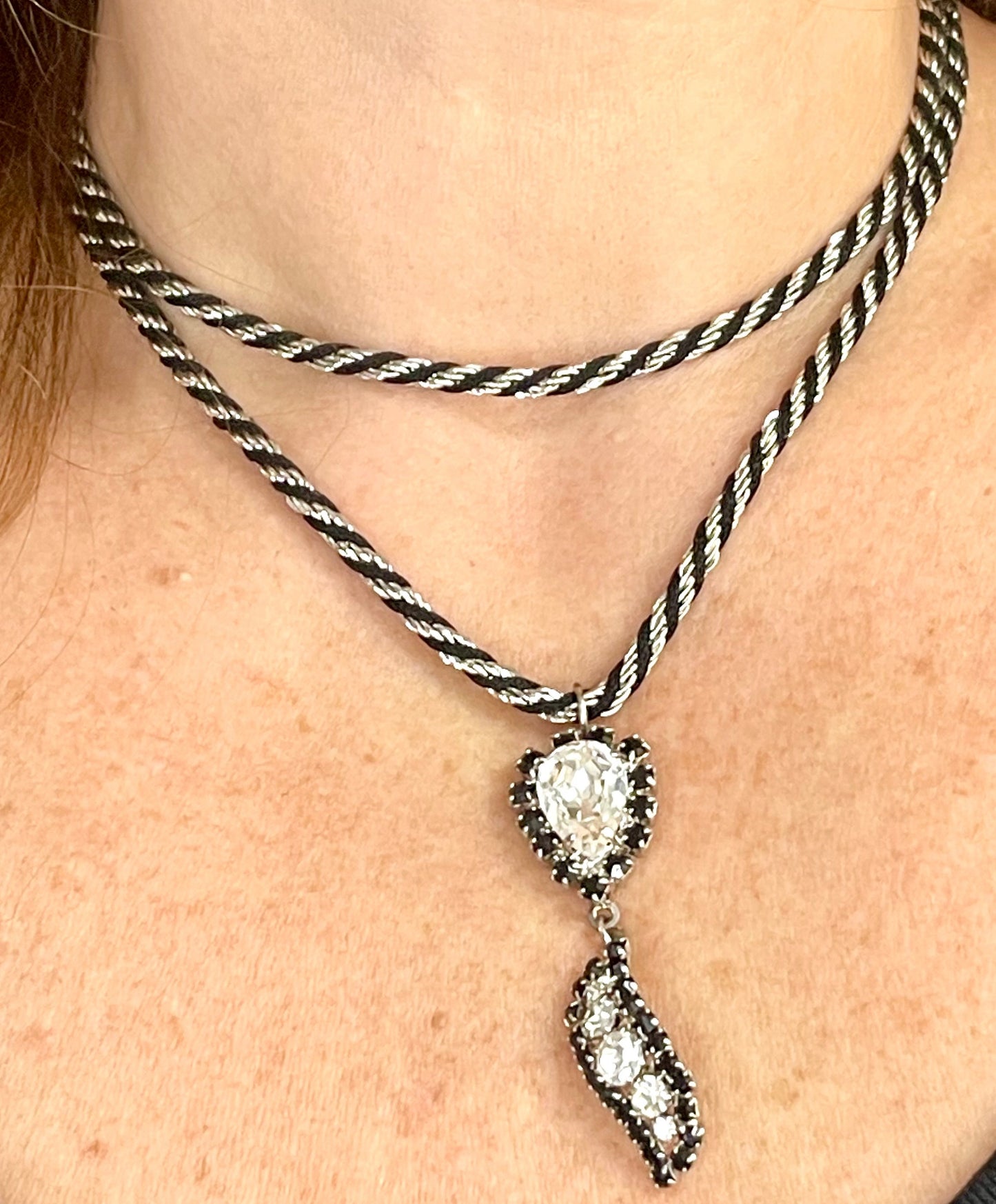 Close up worn on chest , Vintage Trifari silver-tone rope necklace with black cord featuring an attached Christian Dior crystal pendant,