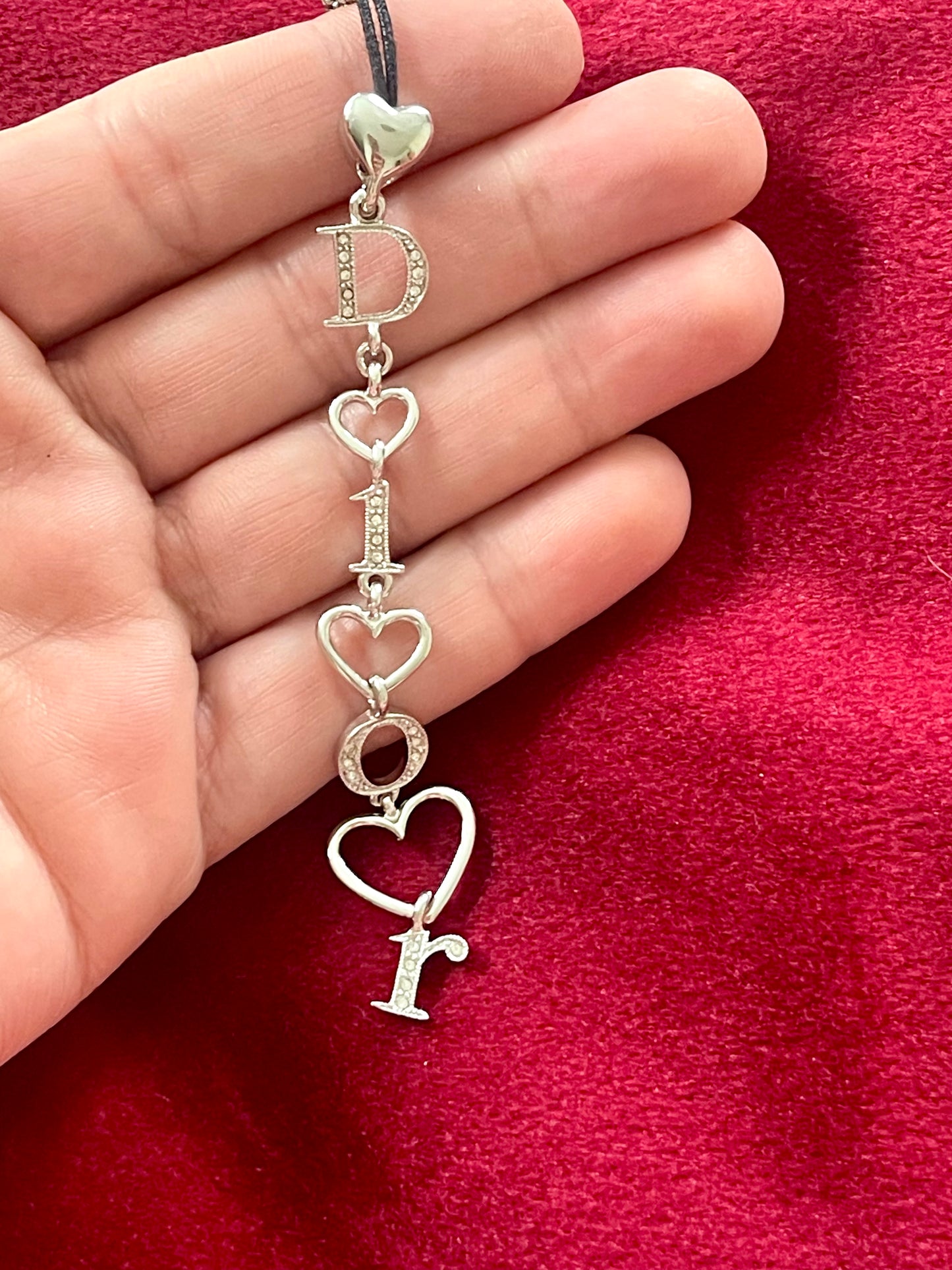 Close-up of Dior phone charm pendant with silver beads and clasp detail, highlighting one-of-a-kind design placed on hand 