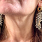 Over view of a pair of Gold and silver earrings with pearl-like beads and YSL Yves Saint Laurent charms worn by model
