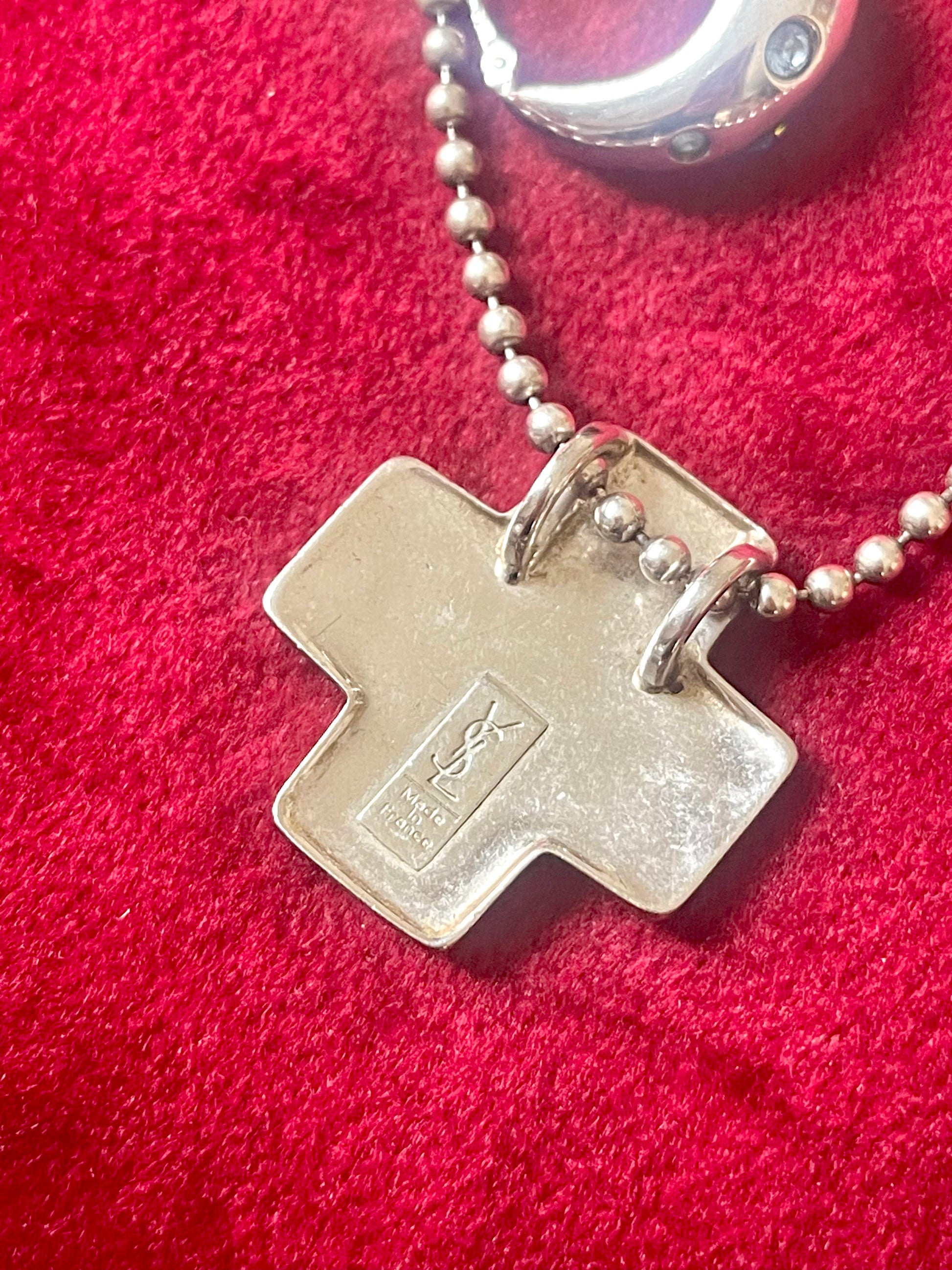 Close-up of back side vintage YSL jewelry, cross pendant necklace Showing the hallmarks 