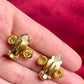 Close up back view Yves Saint Laurent vintage gold tone cross clip-on earrings from the 1980s held in hand, showing rounded gold domes and square-cut center stones