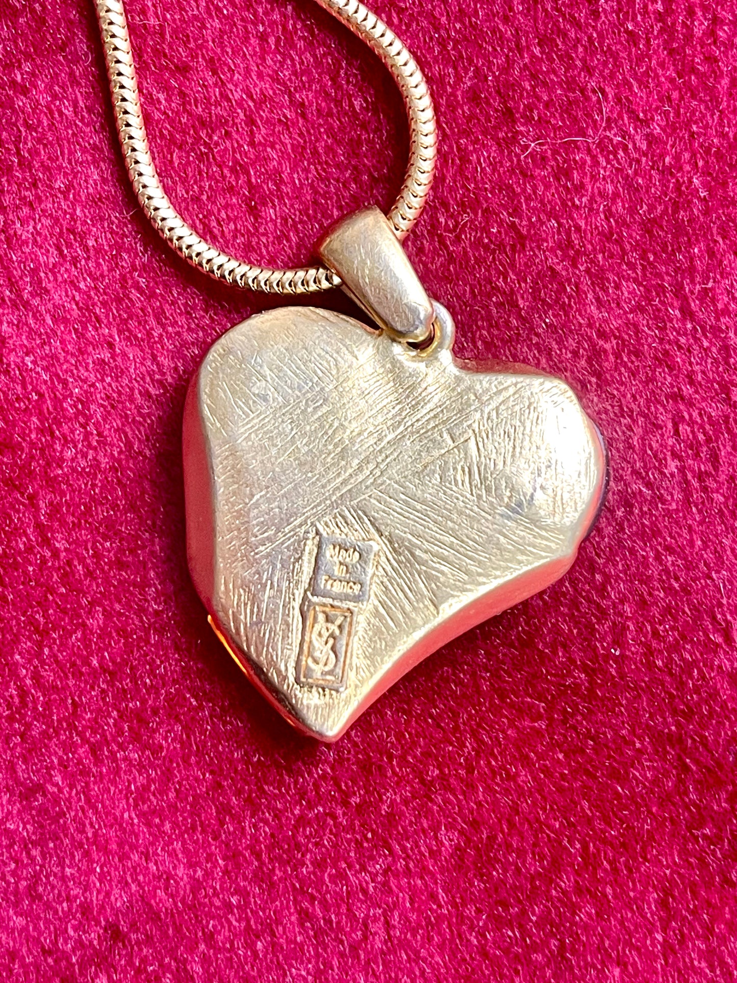 Signed YSL back of orange resin pendant close-up on red background 