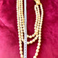 Length 48 cm of YSL faux pearl necklace clasp on red velvet background highlighting the gold-tone sculptural design and domed pearl centerpiece