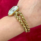 Gold bracelet  YSL with a large crystal on side wrist against a red background