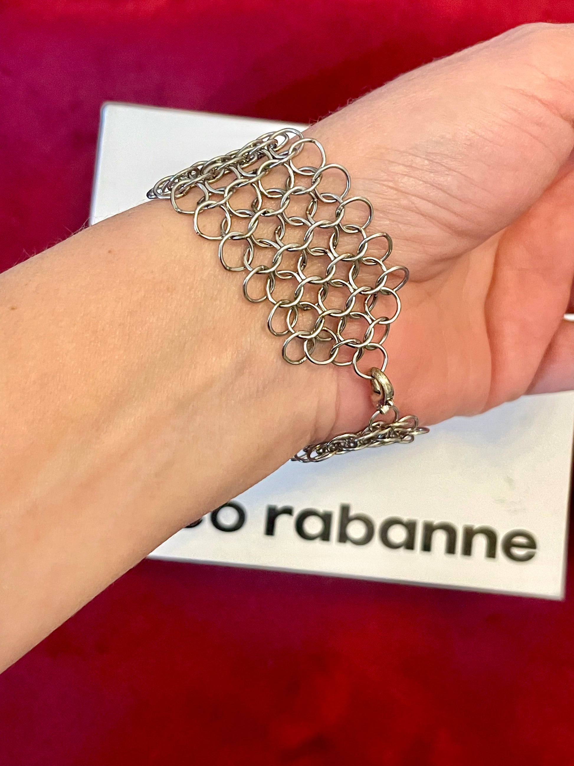Vintage Paco Rabanne bracelet mesh construction close-up On wrist with a red background 