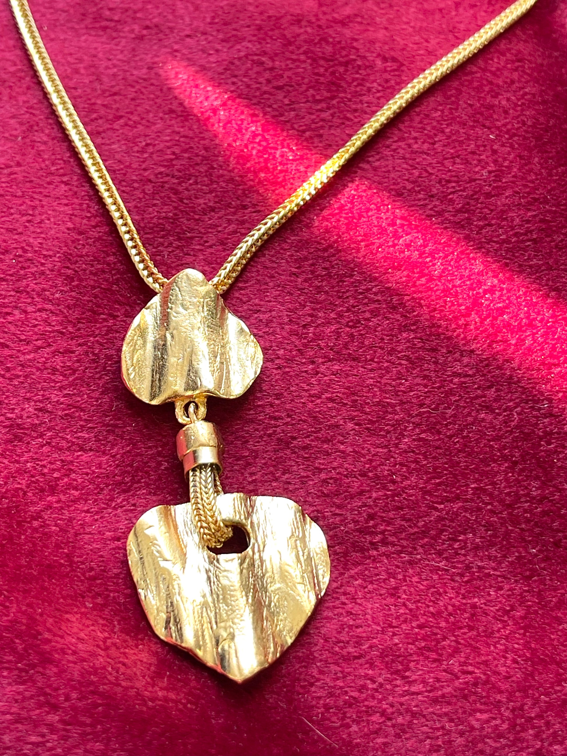 Refurbished 18KG vintage necklace with Arty heart-shaped pendants  from Yves Saint Laurent on a red fabric background