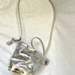 Top view of Paco Rabanne pixel silver vinyl leather bag with structured top flap showing embossed ‘R’ logo and metallic finish.