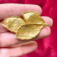 On hand close up Vintage Yves Saint Laurent 80s 90s gold tone leaf brooch excellent condition on red velvet background 
