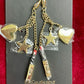 Gold earrings with heart and star charms on a Yves Saint Laurent card against a red background