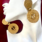 Gold earrings vintage Yves Saint Laurent with circular anchor designs on a white mannequin face 