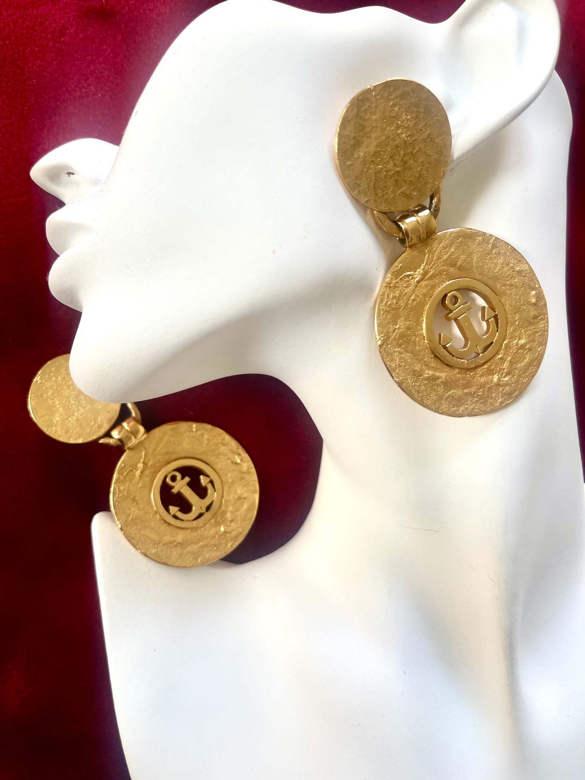 Gold earrings vintage Yves Saint Laurent with circular anchor designs on a white mannequin face 