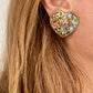 Close up of a person wearing   gold-tone vintage Yves Saint Laurent heart-shaped clip-on earrings decorated with multi-colored crystals vintage 80s