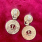 Back of Yves Saint Laurent gold-tone anchor earrings with engraved signatures red background 