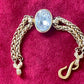 YSL gold tone statement bracelet with oval crystal centerpiece On a red background 