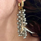 Gold and silver earring with dangling beads and YSL charm worn by a person