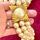 Close-up of gold-tone sculptural clasp with domed faux pearl on a vintage YSL pearl necklace, held in hand to show detail and hallmark