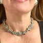 Close-up of a model wearing a vintage Yves Saint Laurent silver necklace with hexagonal YSL Monogram earrings.