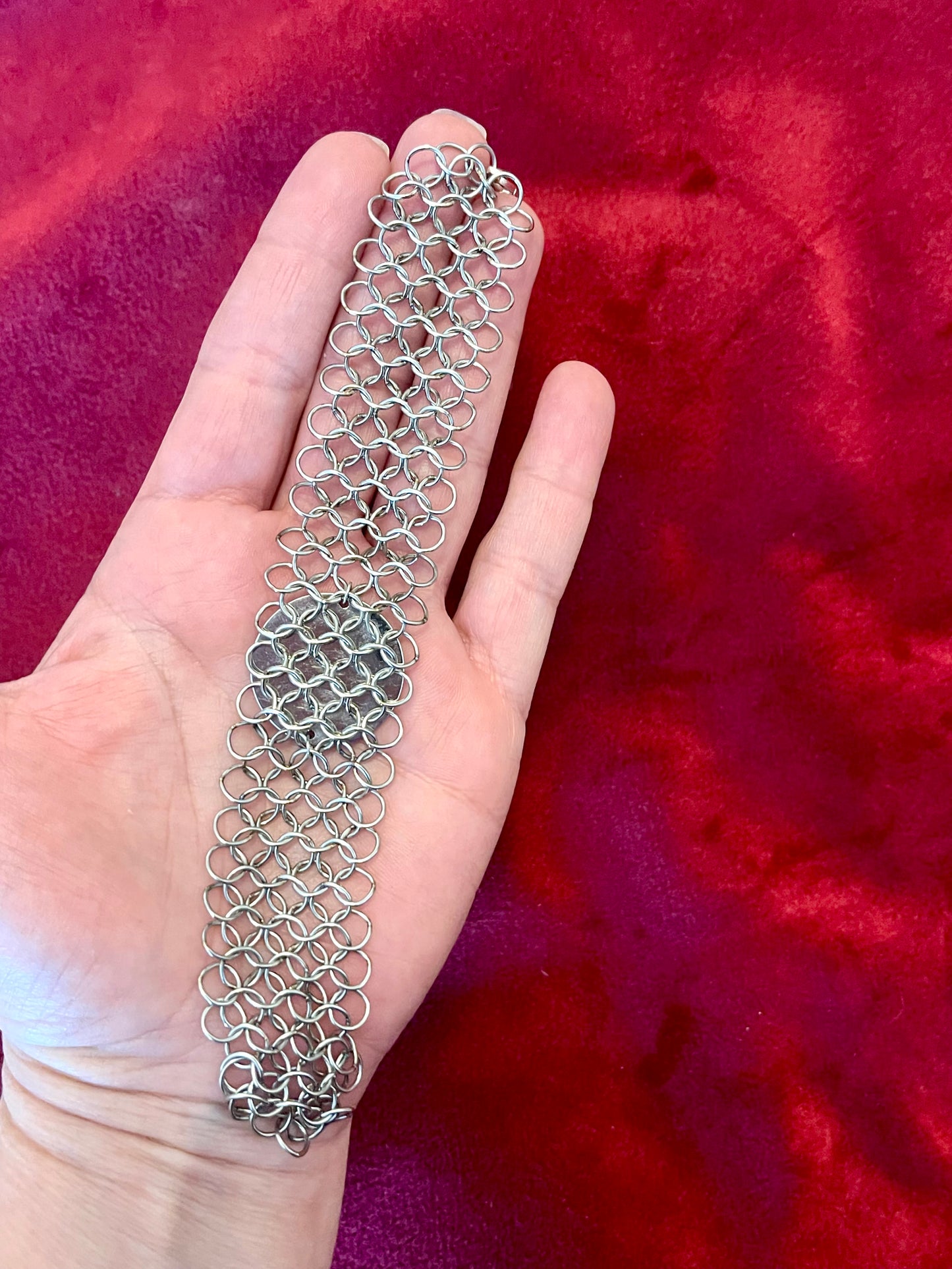 Paco Rabanne silver-tone chainmail bracelet full back view Held on hand with a red background 