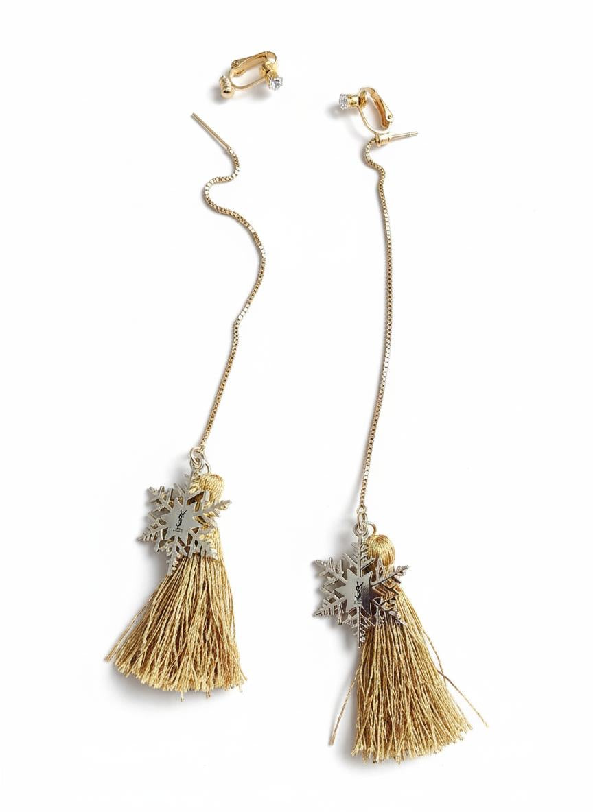 Pair of gold tassel snowflakes charms Yves Saint Laurent earrings with decorative elements on a white background