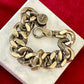 Close up view Preloved YSL bronze and grey chain worn as a statement piece against white background with red velvet 