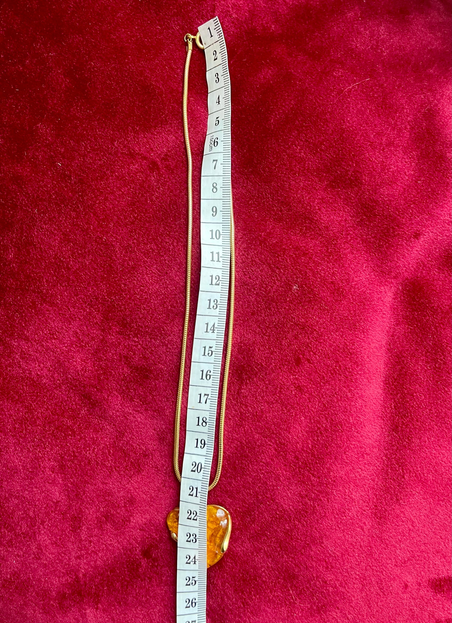 Vintage Yves Saint Laurent orange resin pendant necklace, 24 cm gold‑tone chain With a measuring tape on red background 