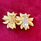 Close up in hallmark signature Orena Paris vintage gold sunflower-shaped earrings on a red background Showing signs of wear 