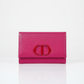 Pink wallet with dior logo on a white background