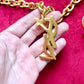 Backside view Displayed on hand Authentic YSL oversized gold logo bag charm pendant repurposed into a long chain necklace, close-up detail vintage Yves Saint Laurent 